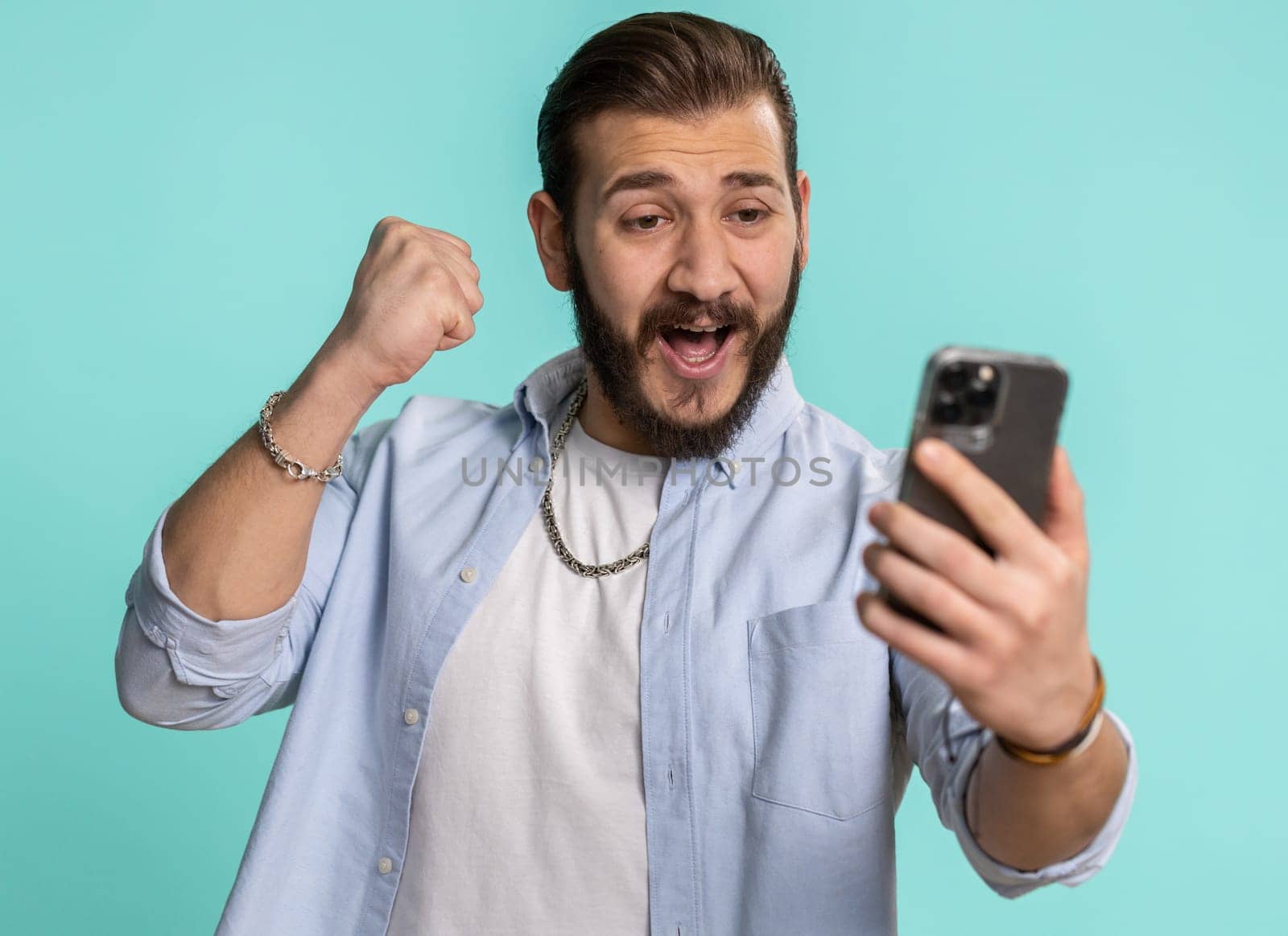 Happy excited joyful lebanese man in black shirt use smartphone typing browsing shouting say wow yes found out great big win, good news, lottery goal achievemen, celebrating success, winning game