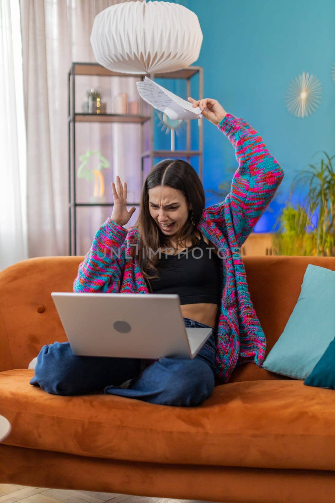 Stressed young woman at home room apartment looking at unpaid bank debt bills, doing paperwork, planning budget, calculate finances mortgage payments. Caucasian displeased girl throws paper bills