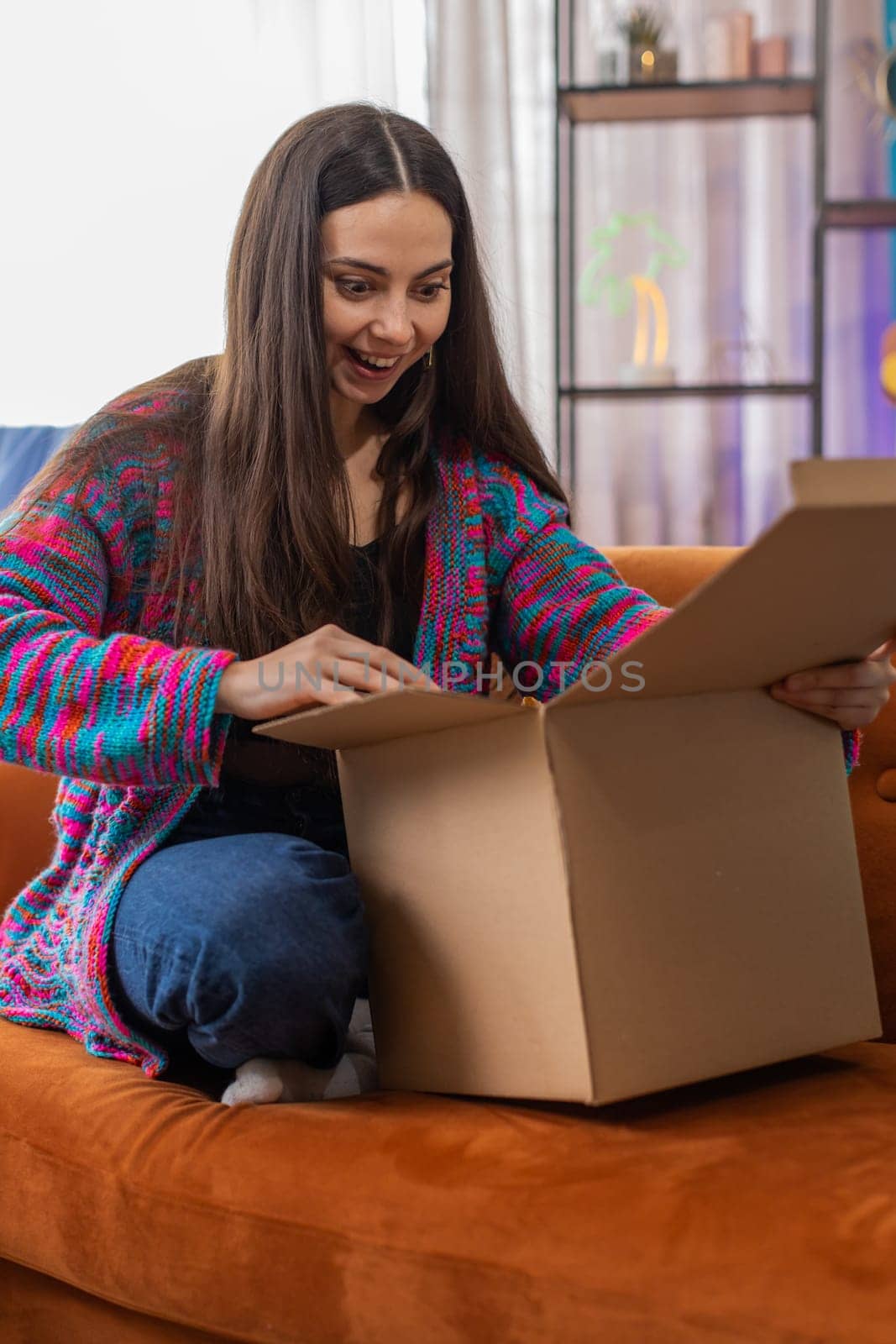 Happy young woman shopper unpacking cardboard box delivery parcel online shopping purchase at home by efuror