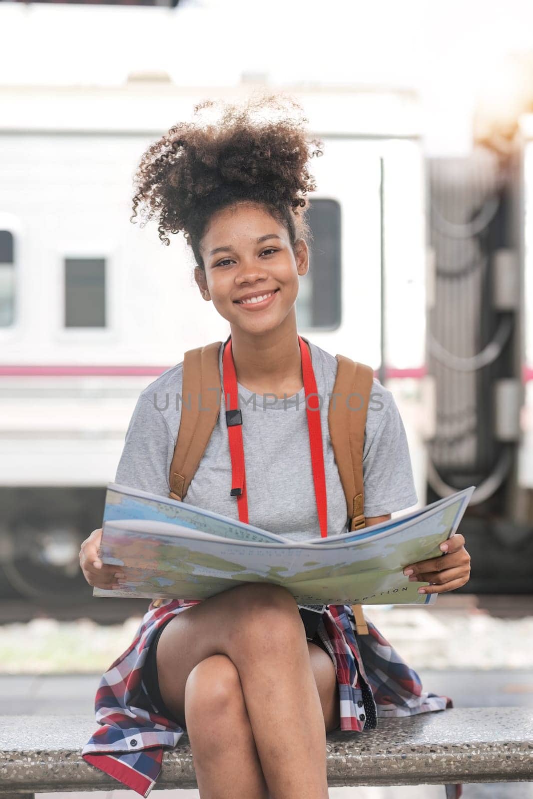 Young woman female smiling traveler with back pack looking to map while waiting for the train at train station. High quality photo..