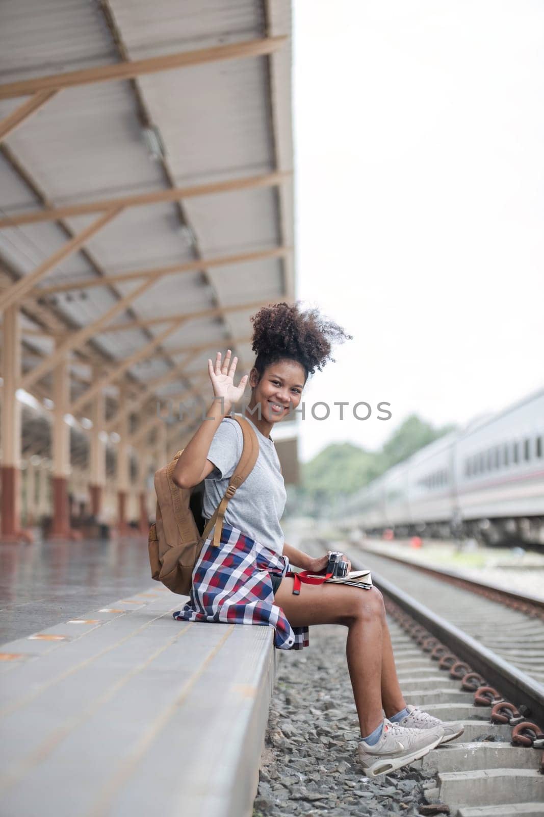 Young woman female smiling traveler with back pack looking to map while waiting for the train at train station. High quality photo..
