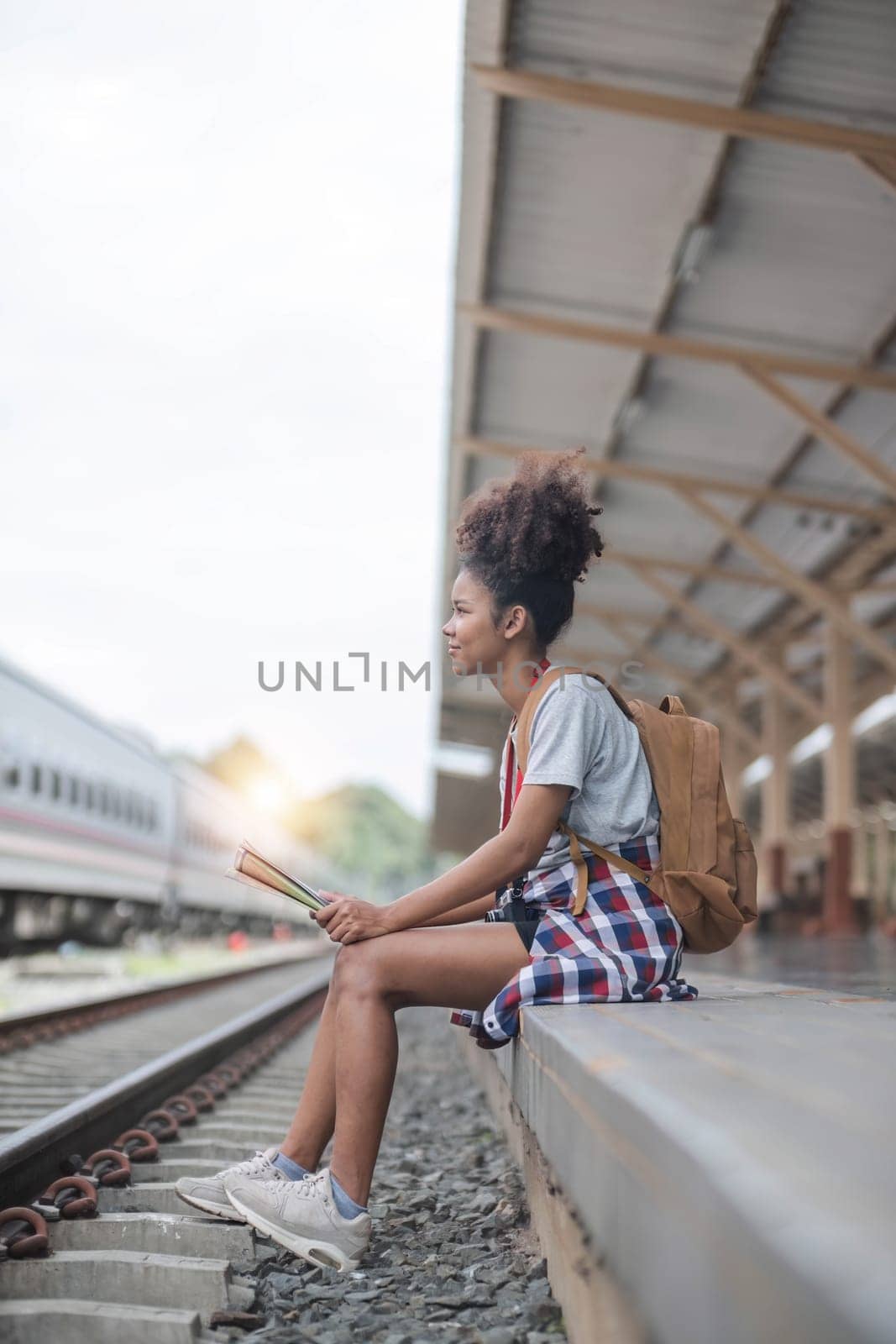 Young woman female smiling traveler with back pack looking to map while waiting for the train at train station. High quality photo by wichayada