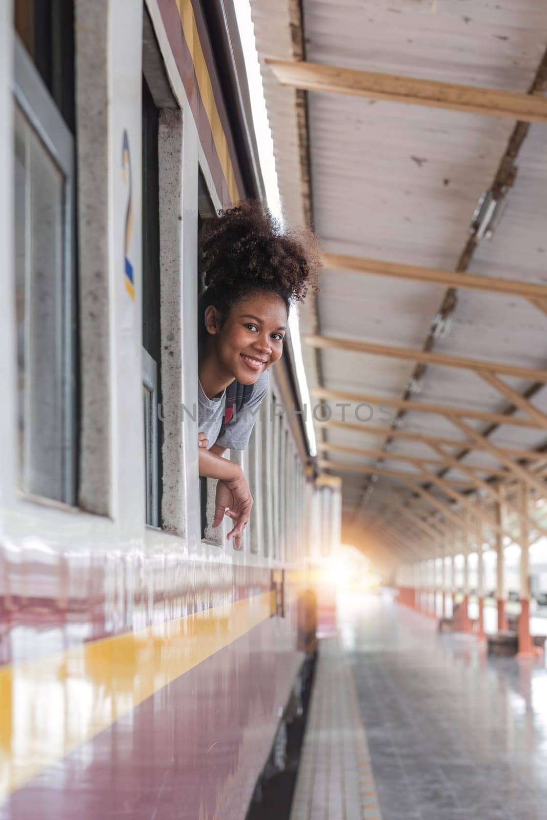 Young asian travel by train sticking her head out of the train. Happy smiling woman female girl looks out from train window travelling by train
