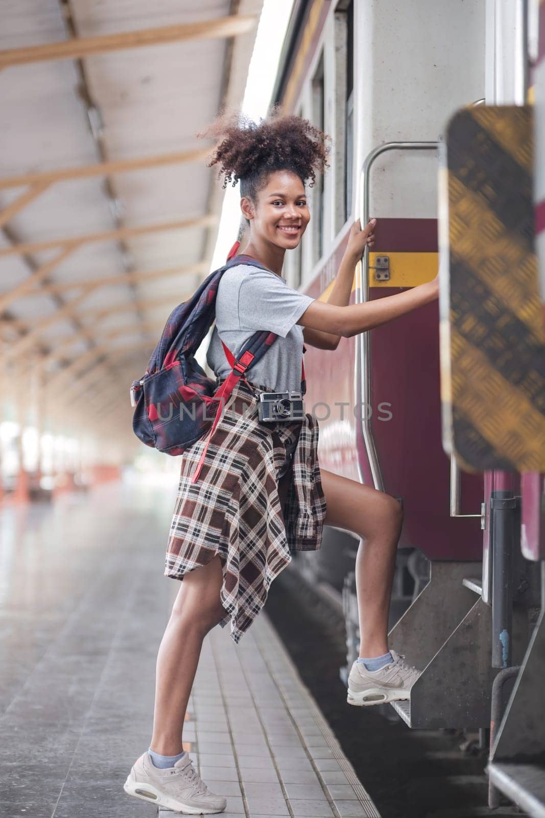 Traveler african asian american woman getting in a train to hop on train, Young woman female standing on train door peeking out looking from door, tourist on a train staion by wichayada