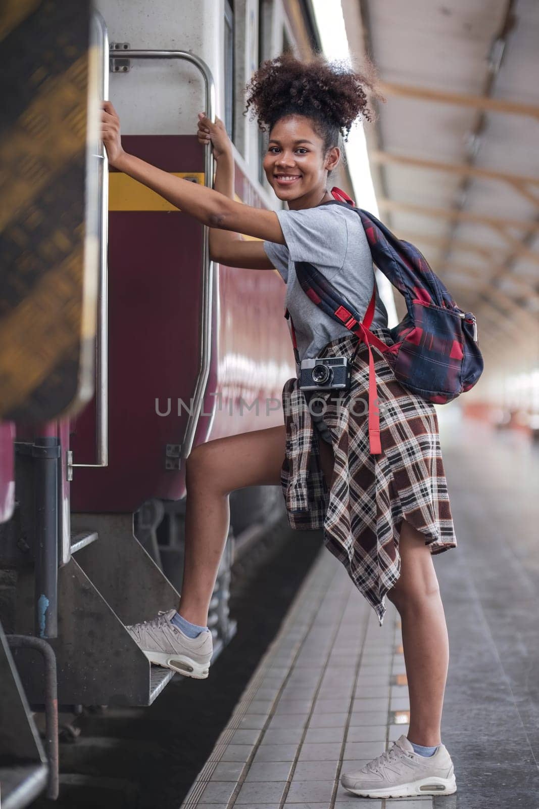 Traveler african asian american woman getting in a train to hop on train. Young woman female standing on train door peeking out looking from door, tourist on a train staion