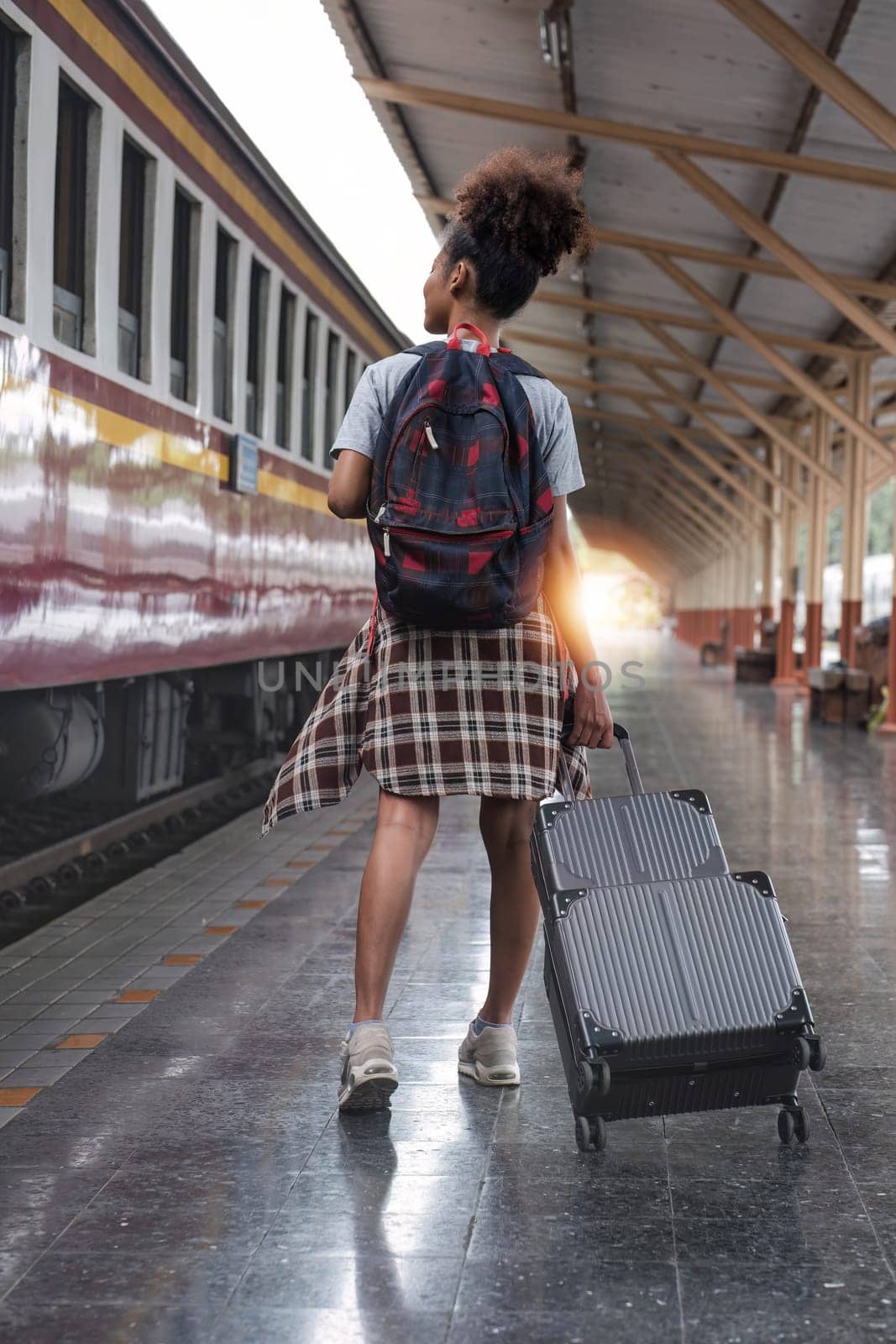 Young female traveler walking standing with a suitcase at train station. woman traveler tourist walking standing smiling with luggage at train station by wichayada