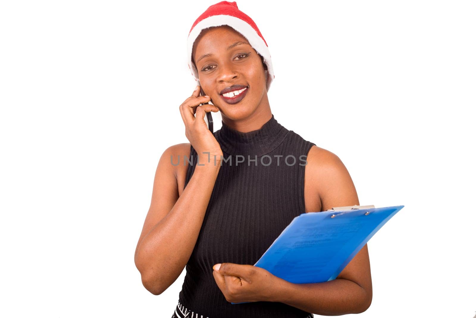 Smiling woman wearing christmas hat, talking on the phone ready to write goals on a blank list for new year.