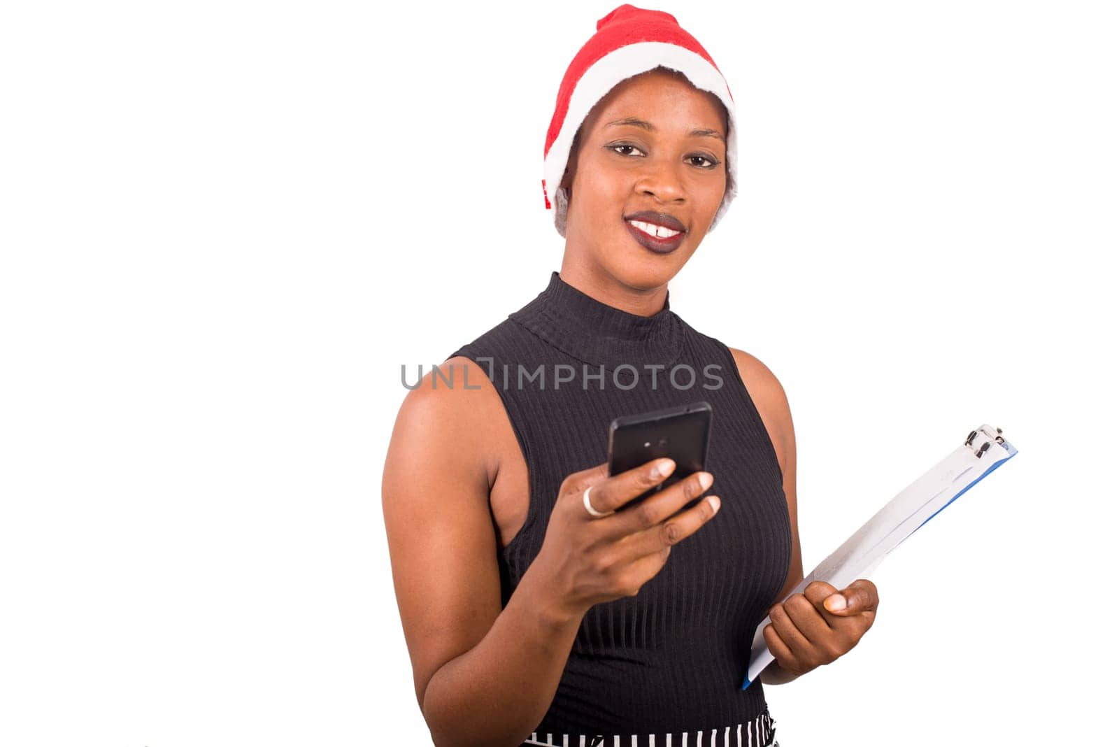 Smiling woman wearing christmas hat, talking on the phone ready to write goals on a blank list for new year.