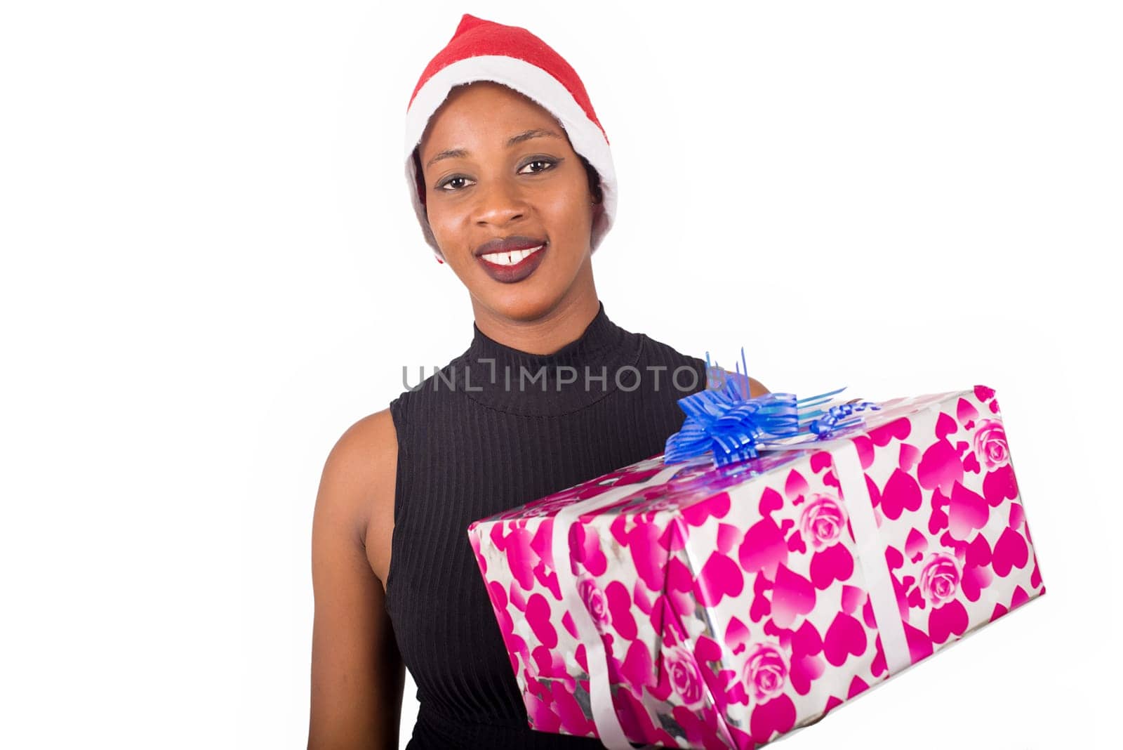 young woman standing in a hat looking at the camera smiling with a package in hand.