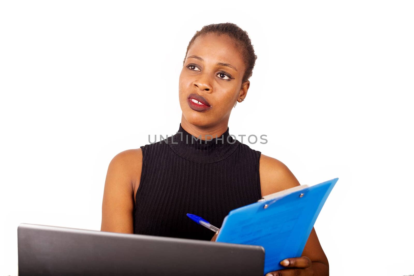 Young confident secretary or office manager sitting in front of his office and writing his business plan in front of his laptop