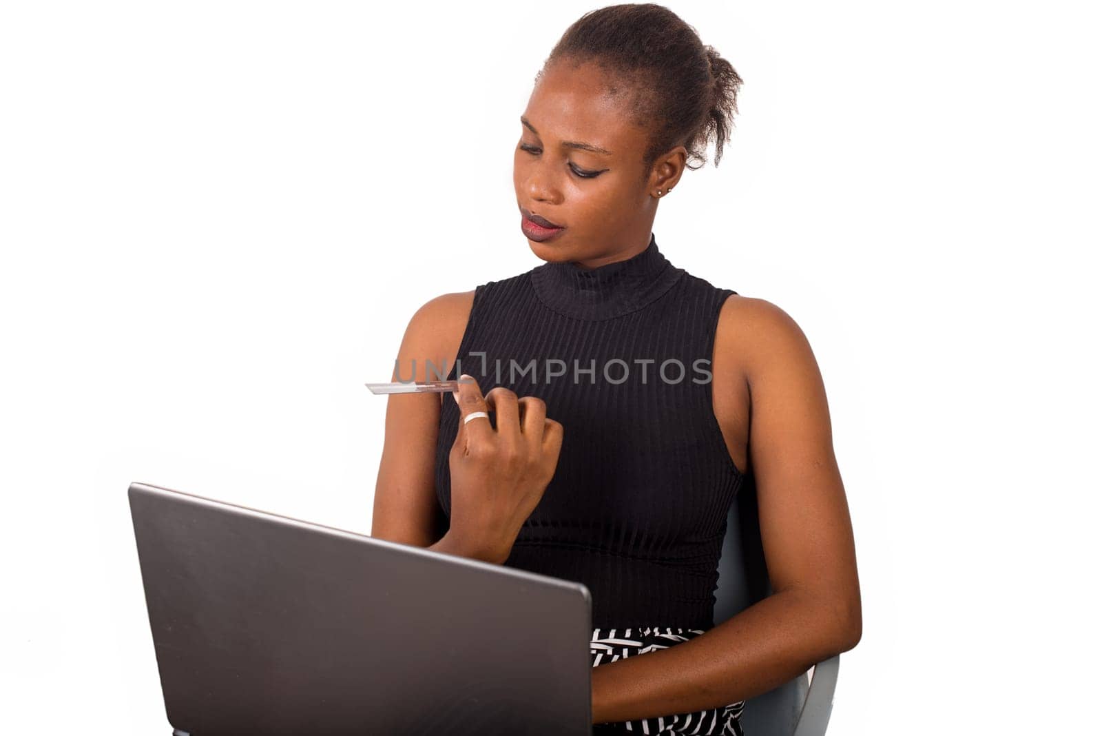 young woman sitting with laptop computer looking at credit card.
