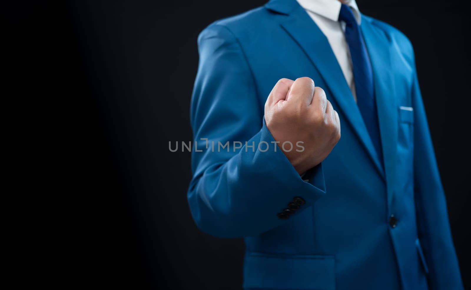 Businessman in blue suit and showing fist on a fresh background. by Unimages2527