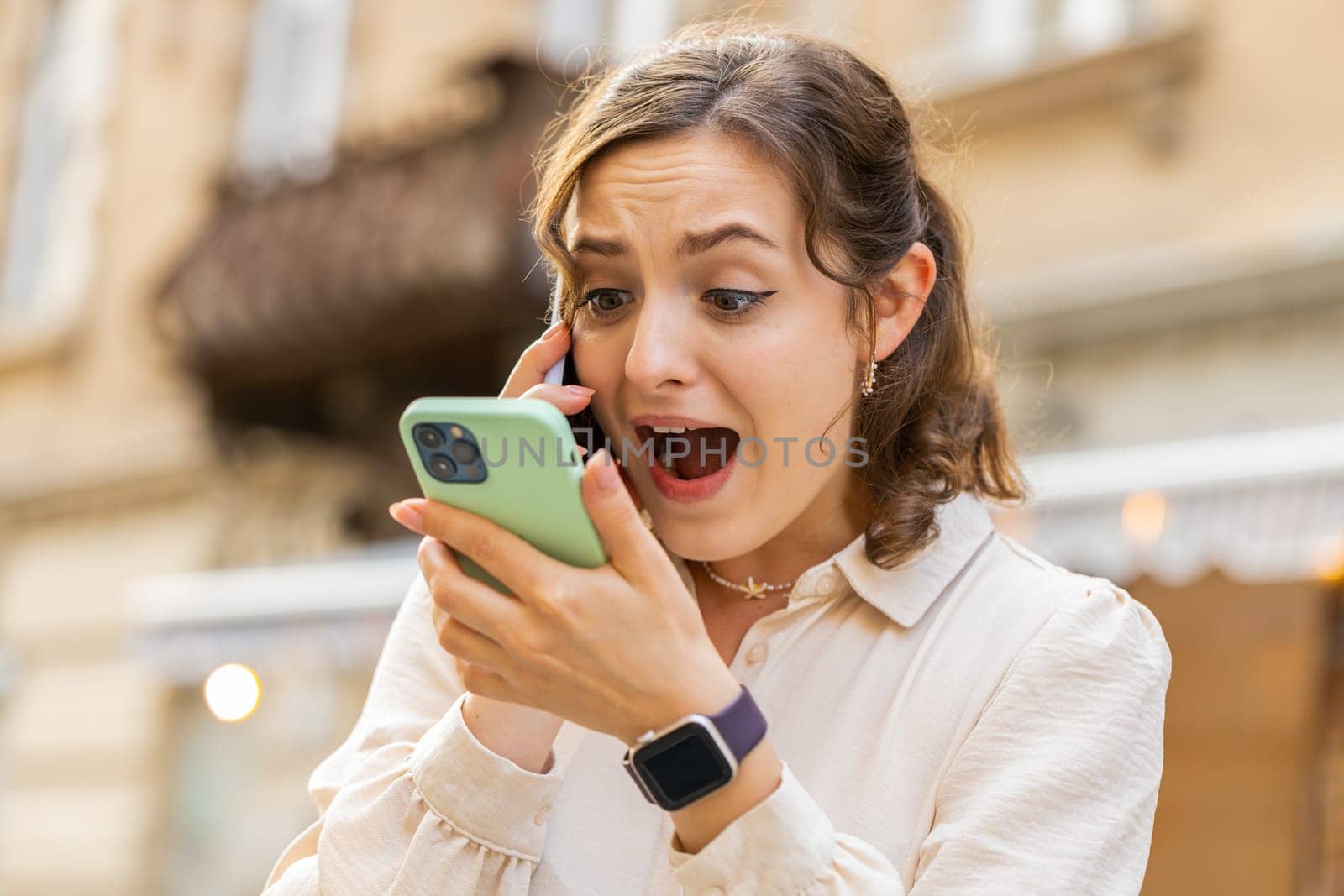 Irritated nervous stressed young woman talking screaming on two mobile phones having conversation conflict quarrel complaint dispute discuss solve problem outdoors. Girl walking in urban city street