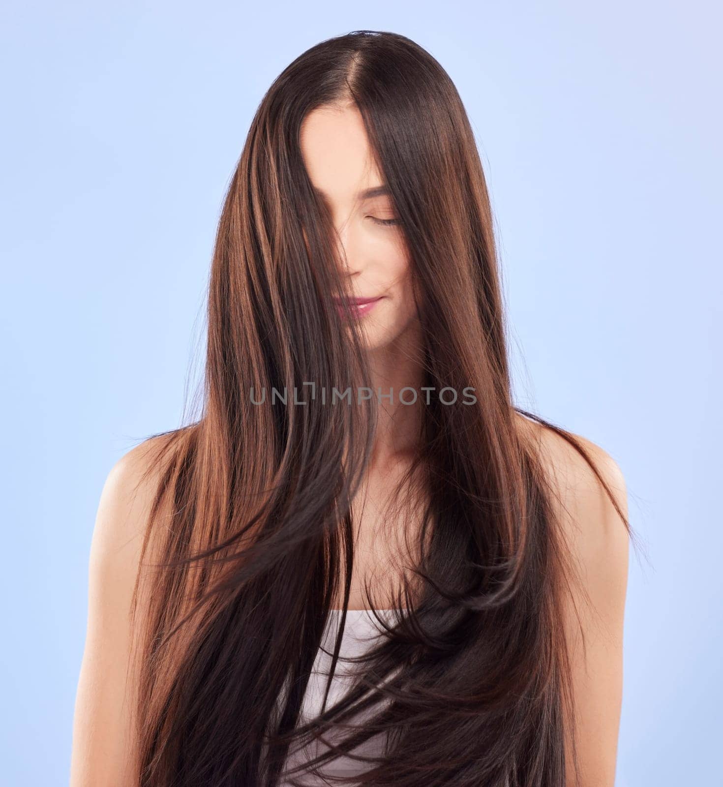 Beauty, texture and woman with hair care, growth and wellness against a blue studio background. Female person, aesthetic and model with volume, scalp treatment and luxury with shampoo and cosmetics by YuriArcurs