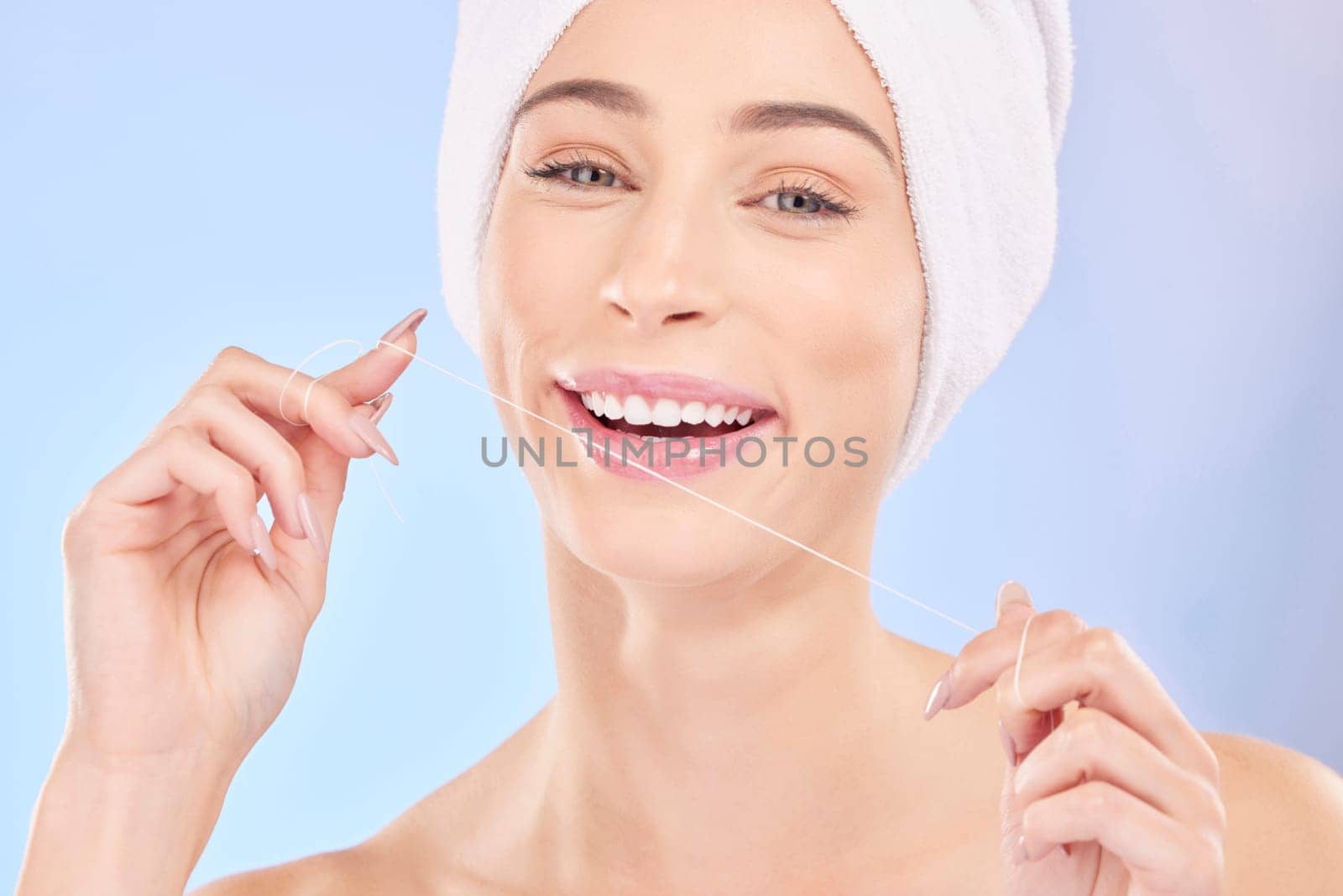 Flossing, teeth and woman in portrait, dental and health with oral care isolated on blue background. Female model, morning routine and orthodontics, hygiene and cleaning mouth with thread in studio.