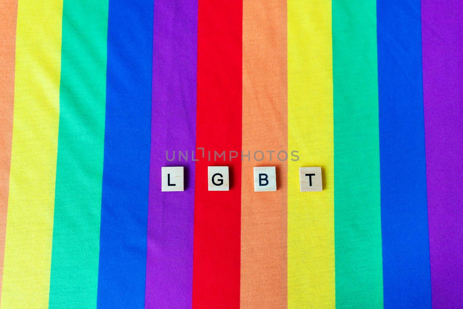 LGBT community, bright rainbow flag, wooden lettering. The rights of all people on the planet, hands in the frame, vertical photo