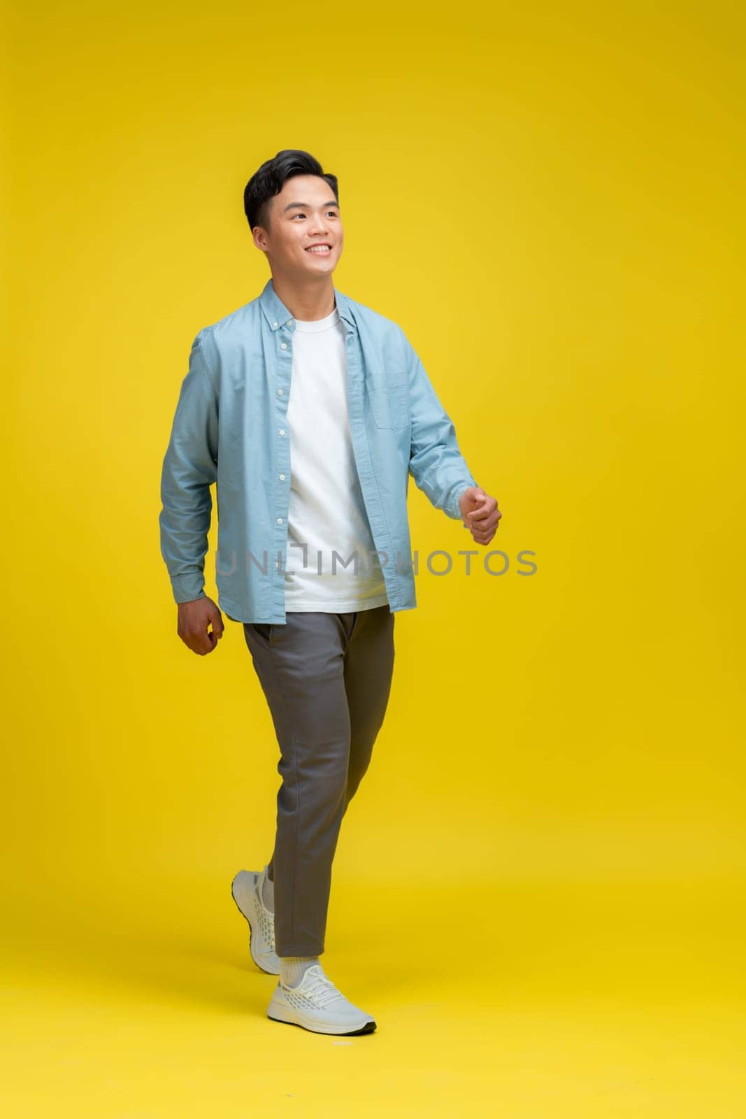 Full body photo of charming happy young man look empty space isolated on yellow background