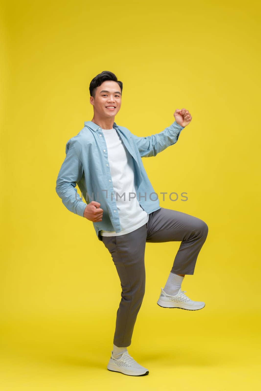  Portrait of young male cheerful confident and excited jump in air and smile at studio. by makidotvn