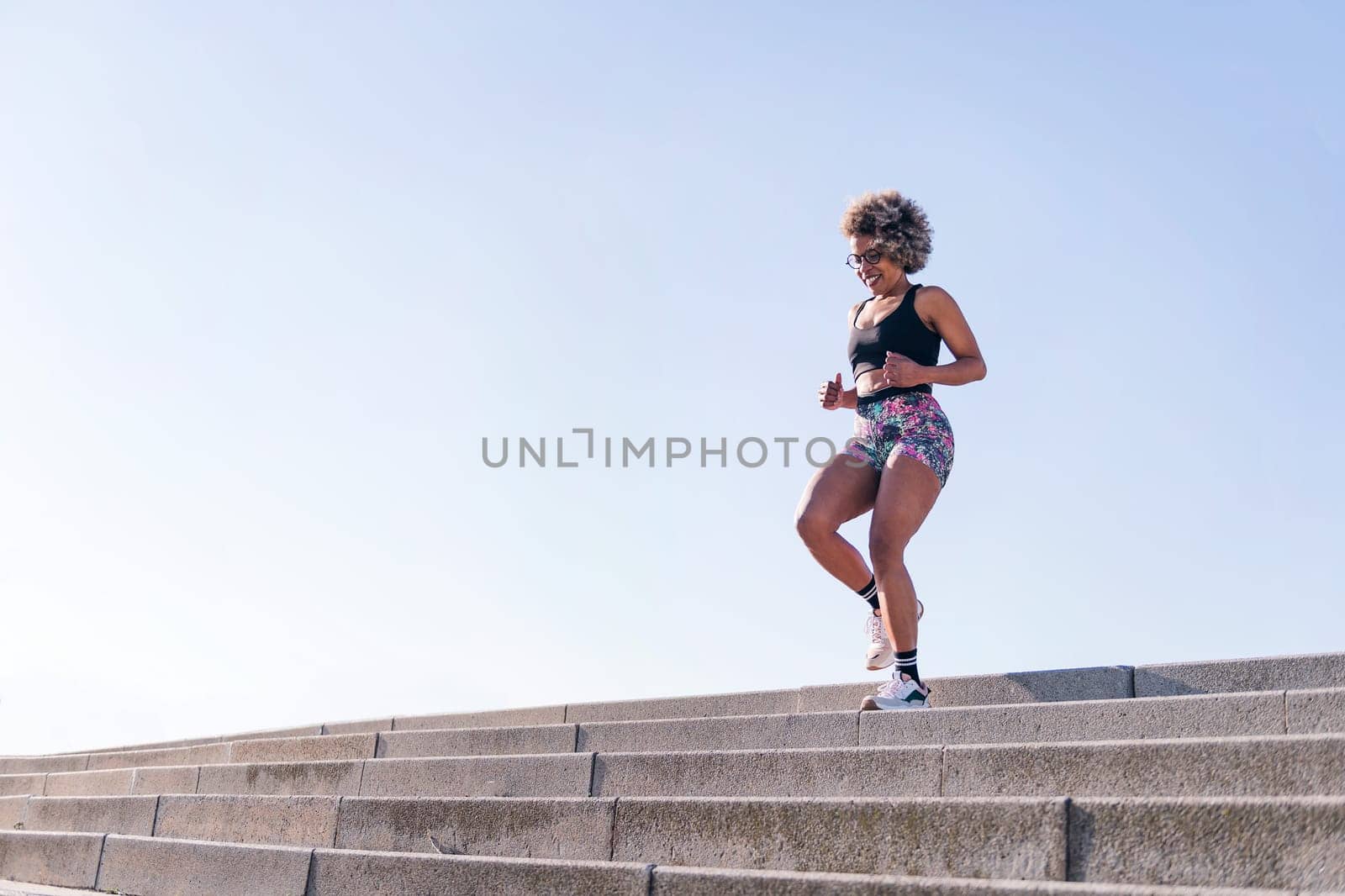 strong african american woman running down stairs outdoors, concept of sports and active lifestyle, copy space for text