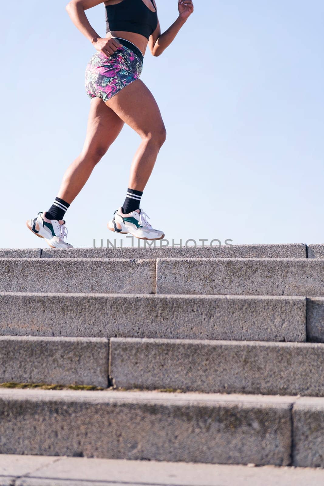 vertical cropped photo of the legs of an unrecognizable african american woman running outdoors, concept of sports and active lifestyle, copy space for text