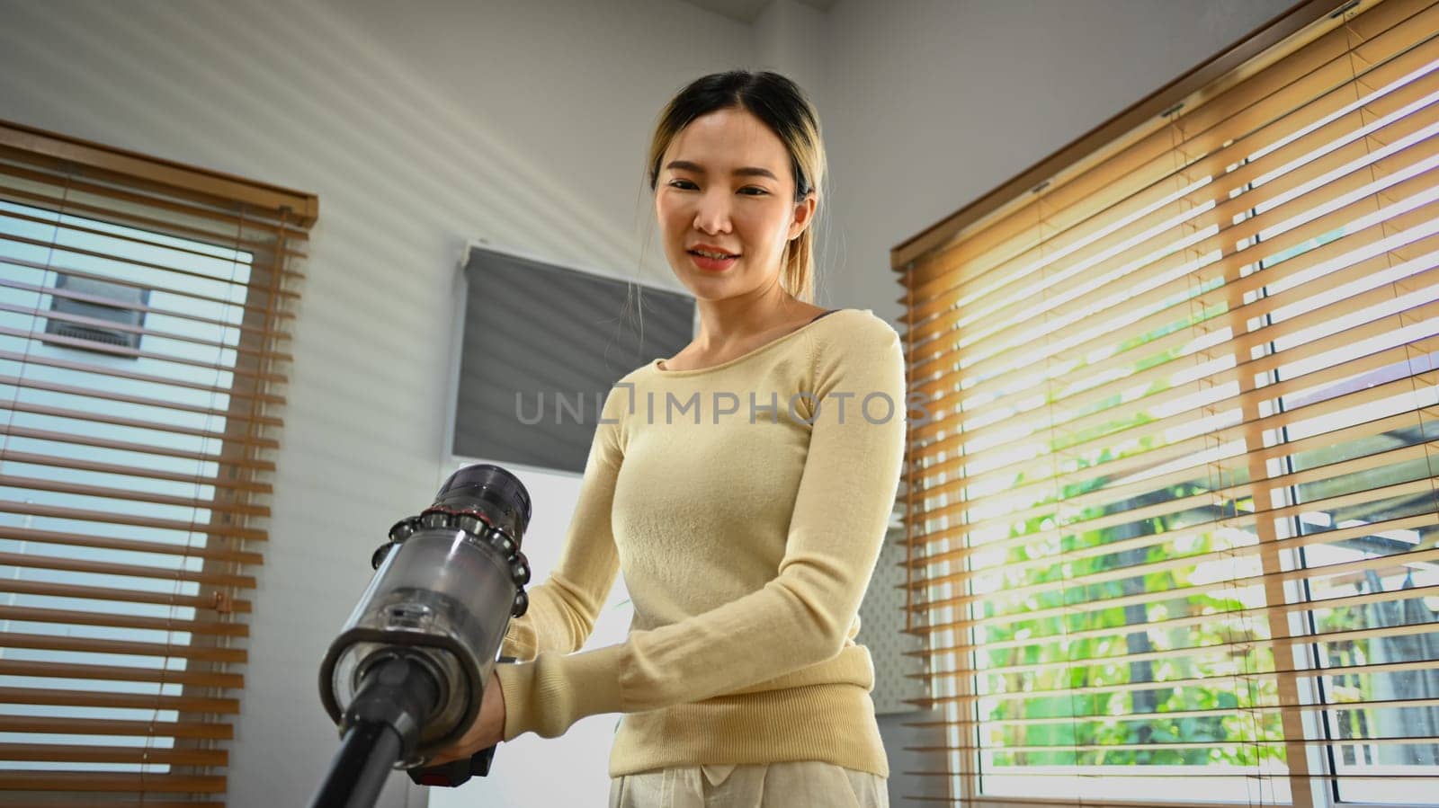 Smiling Asian housewife vacuuming and wiping dirty on the floor in living room. House cleaning and housework concept.