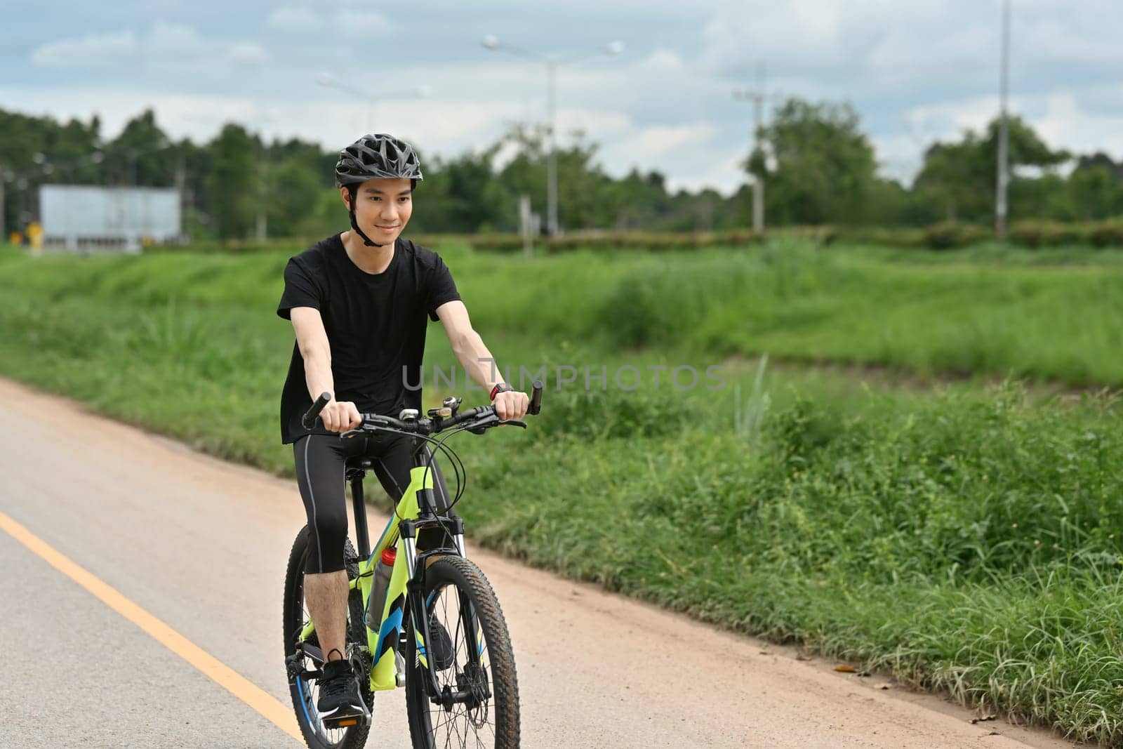 Shot of happy asian guy enjoying biking in the summer park. Sport, leisure and healthy lifestyle concept.