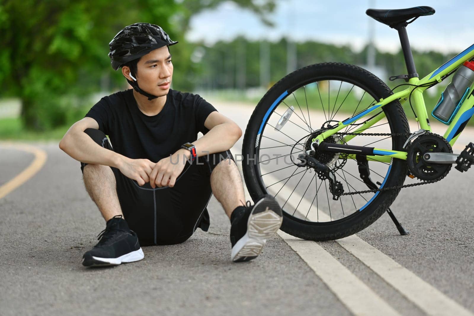 Man in sport clothes taking a break from cycling bike in the morning. Outdoor sport activity and healthy lifestyle concept.