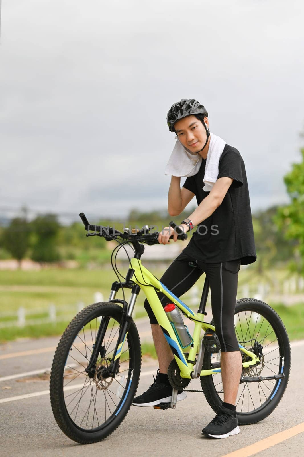 Full length of man with towels sitting on his bicycle, taking a break during cycling in a park by prathanchorruangsak