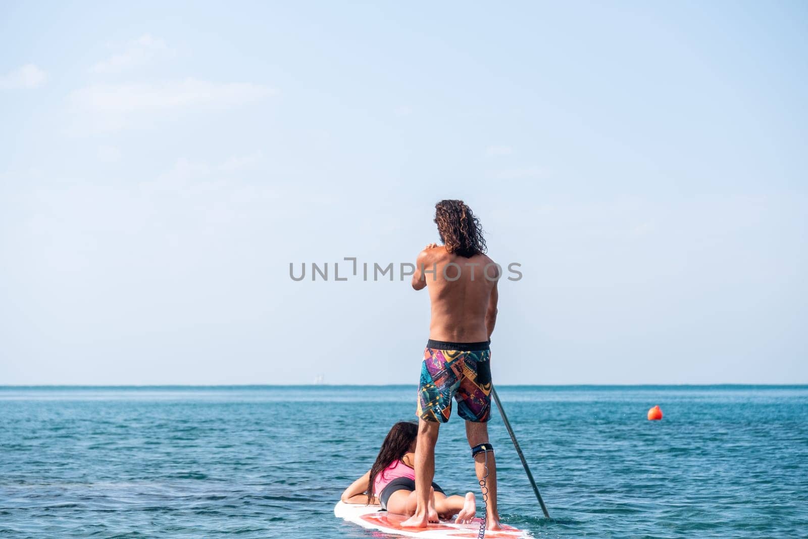 Silhouette of woman standing, surfing on SUP board, confident paddling through water surface. Idyllic sunset or sunrise. Sports active lifestyle at sea or river.