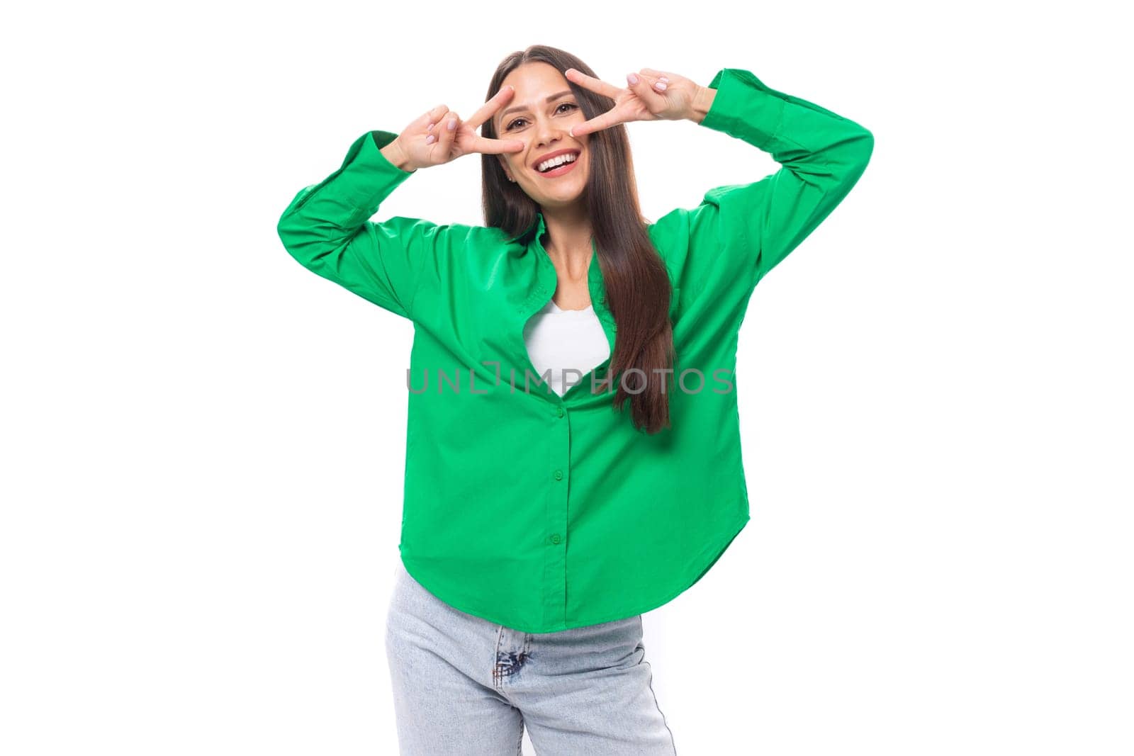 well-groomed slender brunette woman with long hair dressed in a casual green shirt makes faces.