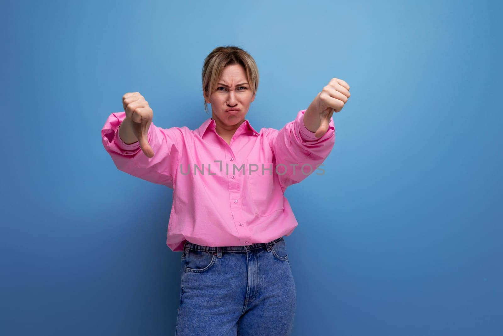 young european blonde secretary woman dressed in a pink shirt shows dislike.