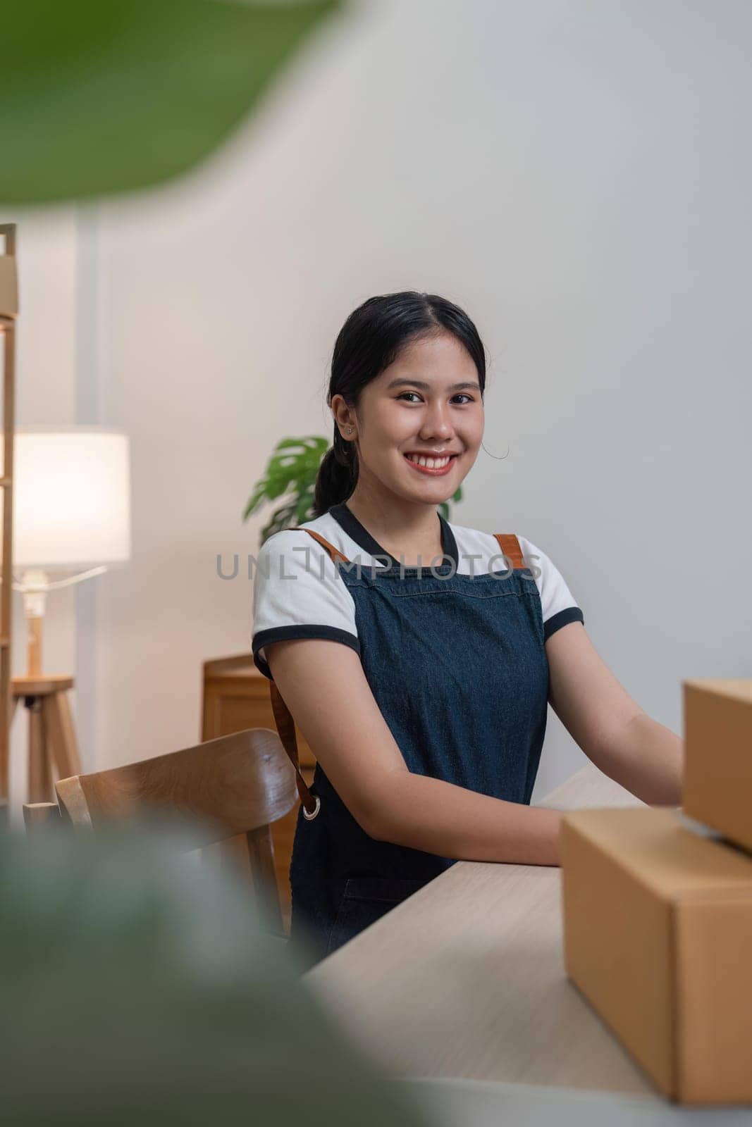Young business woman working online ecommerce shopping at her shop. Young woman seller prepare parcel box of product for deliver to customer. Online selling, ecommerce by nateemee