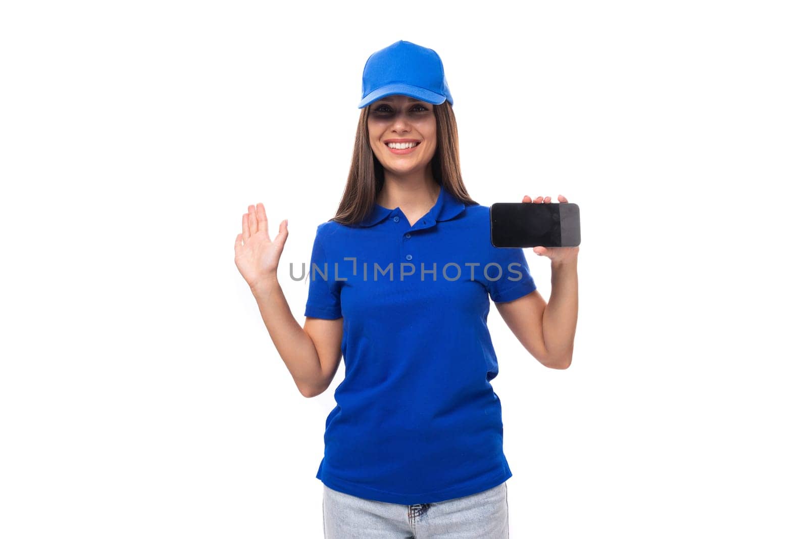 slender young brunette woman in a blue cap and t-shirt shows ads on a smartphone.