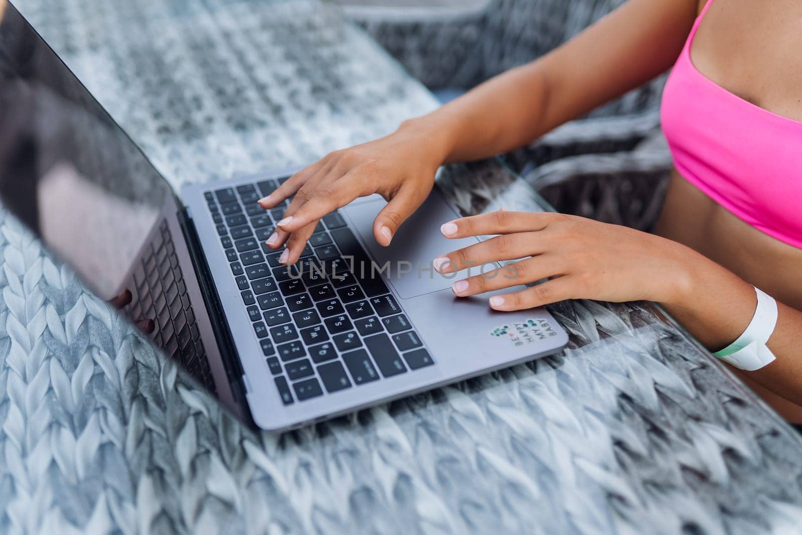 Cute young woman in swimsuit working on laptop sitting on terrace on the beach by teksomolika