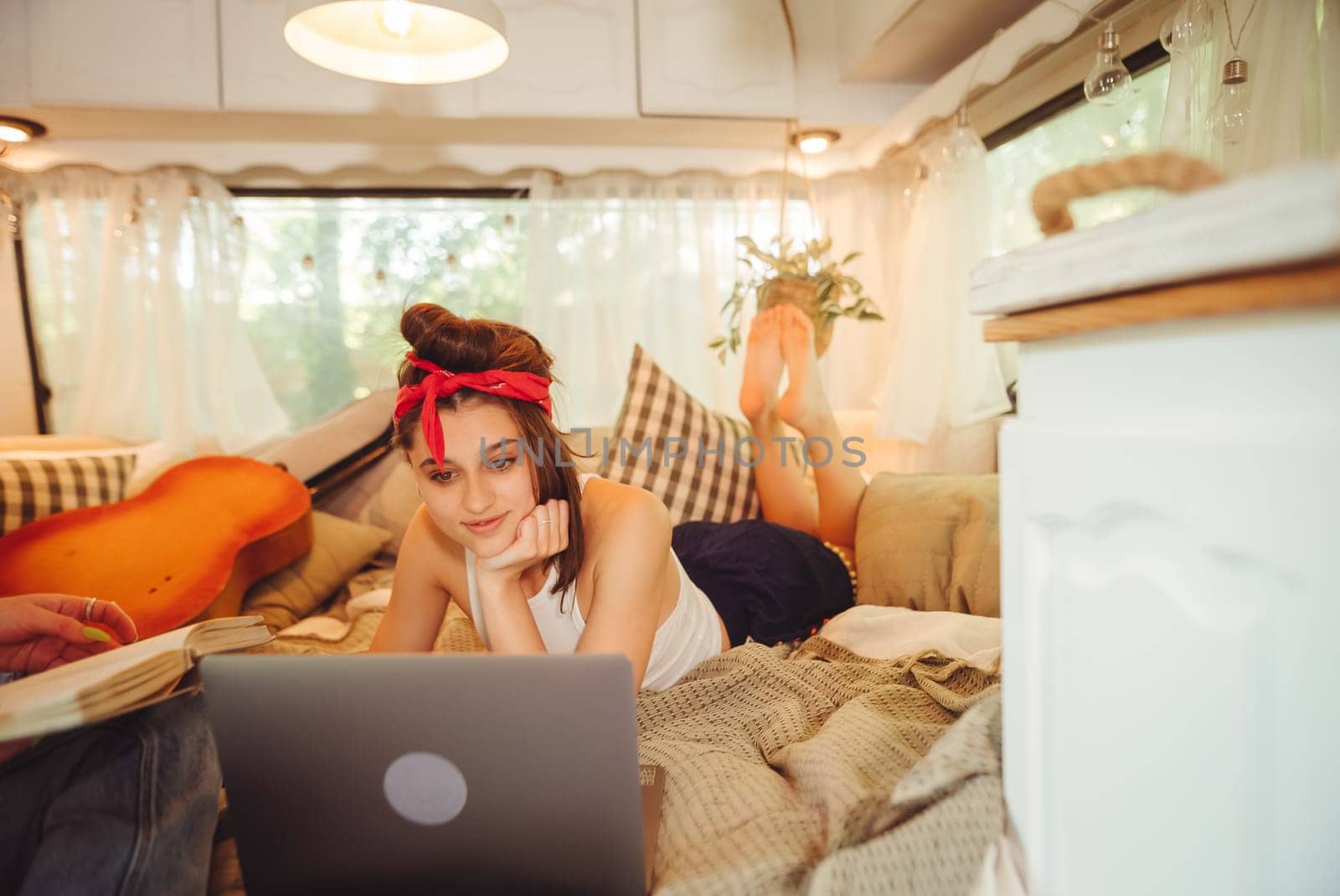 Portrait of a cute lesbian couple. Two girls spend time tenderly together watching movie on laptop in a camper trailer with LGBT flag on the wall. Love and attitude. LGBT concept. High quality photo