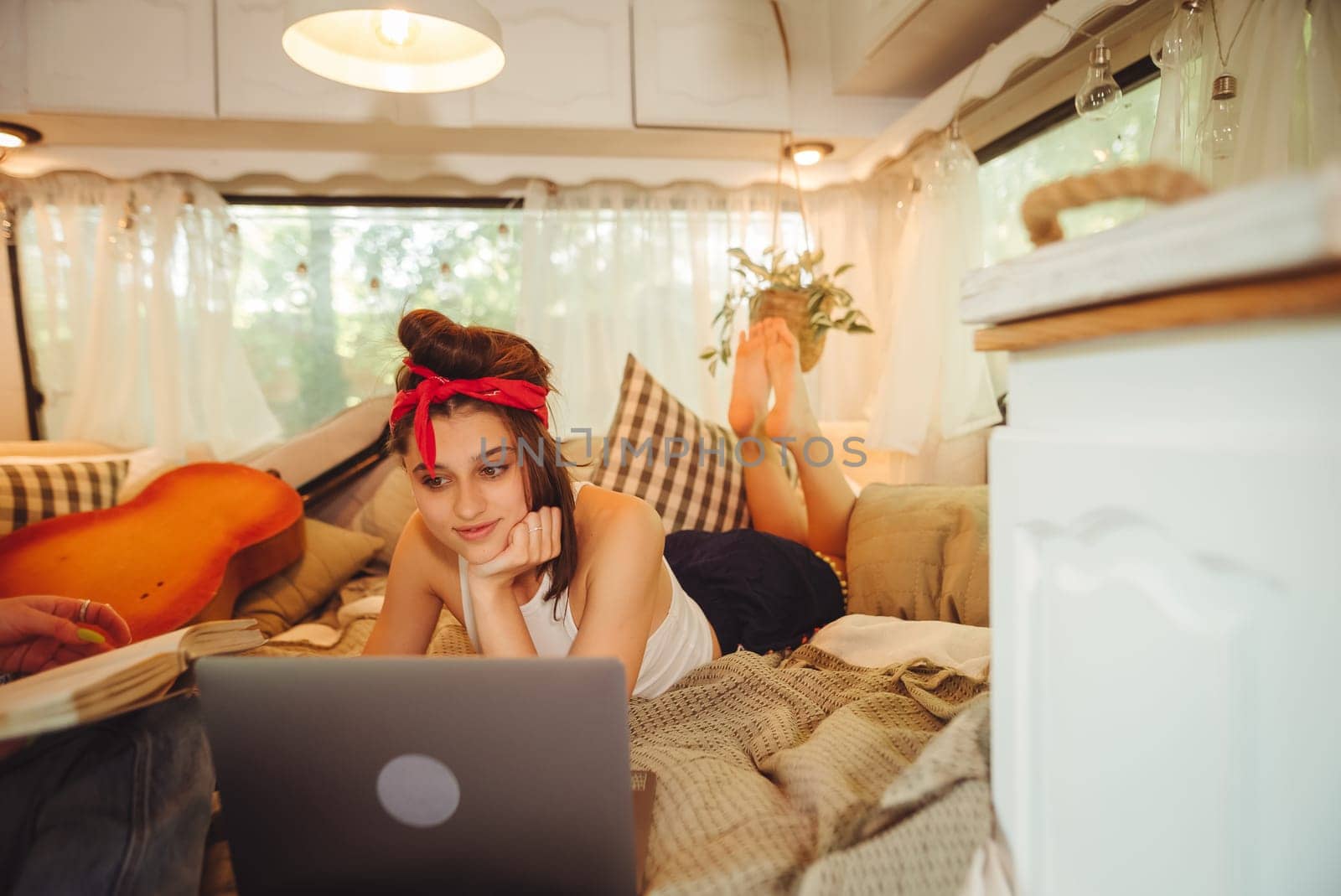 Portrait of a cute lesbian couple. Two girls spend time tenderly together watching movie on laptop in a camper trailer with LGBT flag on the wall. Love and attitude. LGBT concept. High quality photo