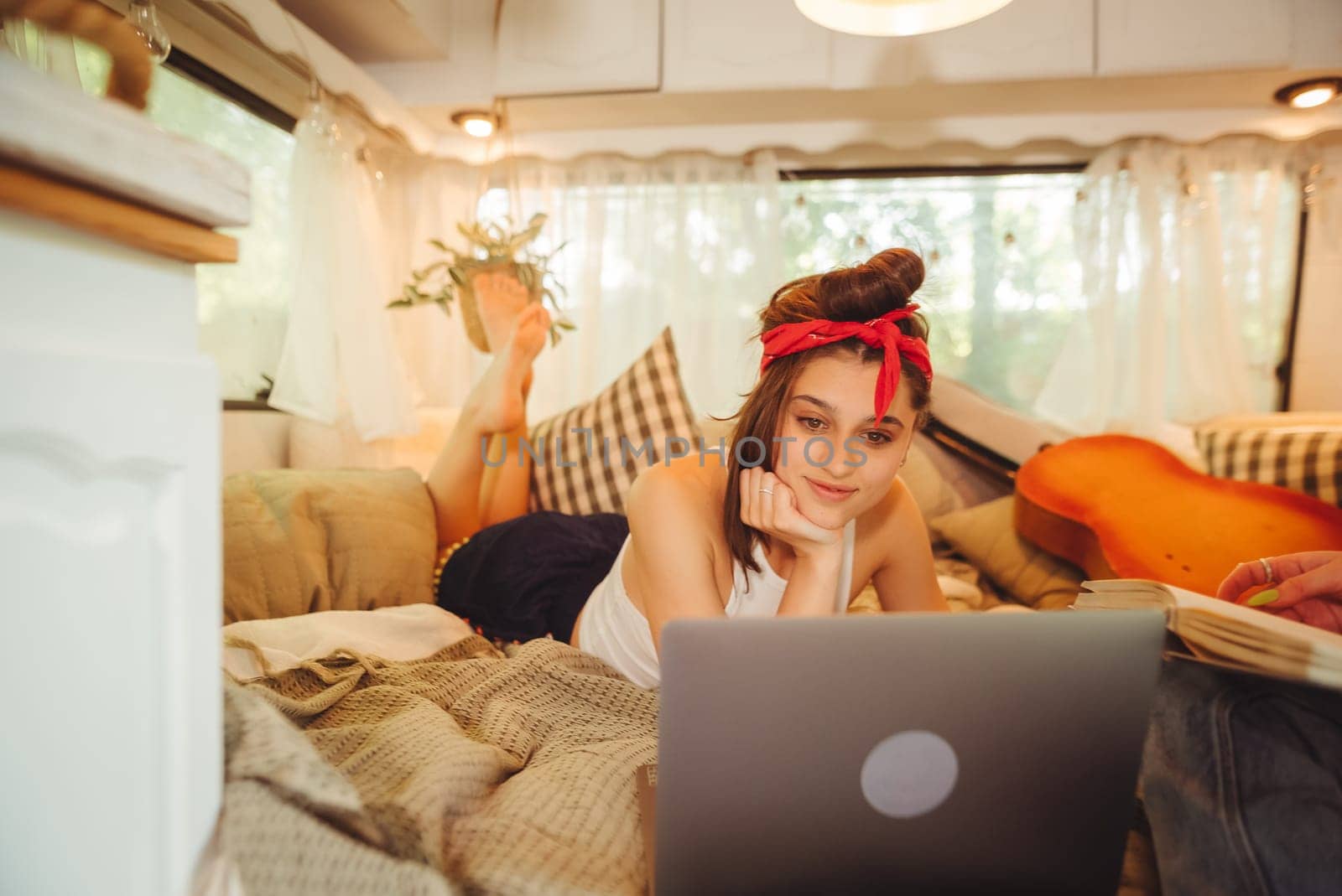 Portrait of a cute lesbian couple. Two girls spend time tenderly together watching movie on laptop in a camper trailer with LGBT flag on the wall. Love and attitude. LGBT concept. High quality photo