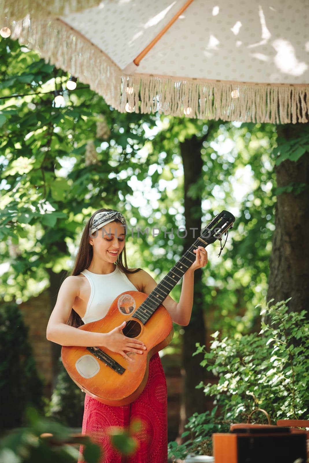 Happy hippie girl is having a good time with playing on guitar in camper trailer. Holiday, vacation, trip concept.High quality photo