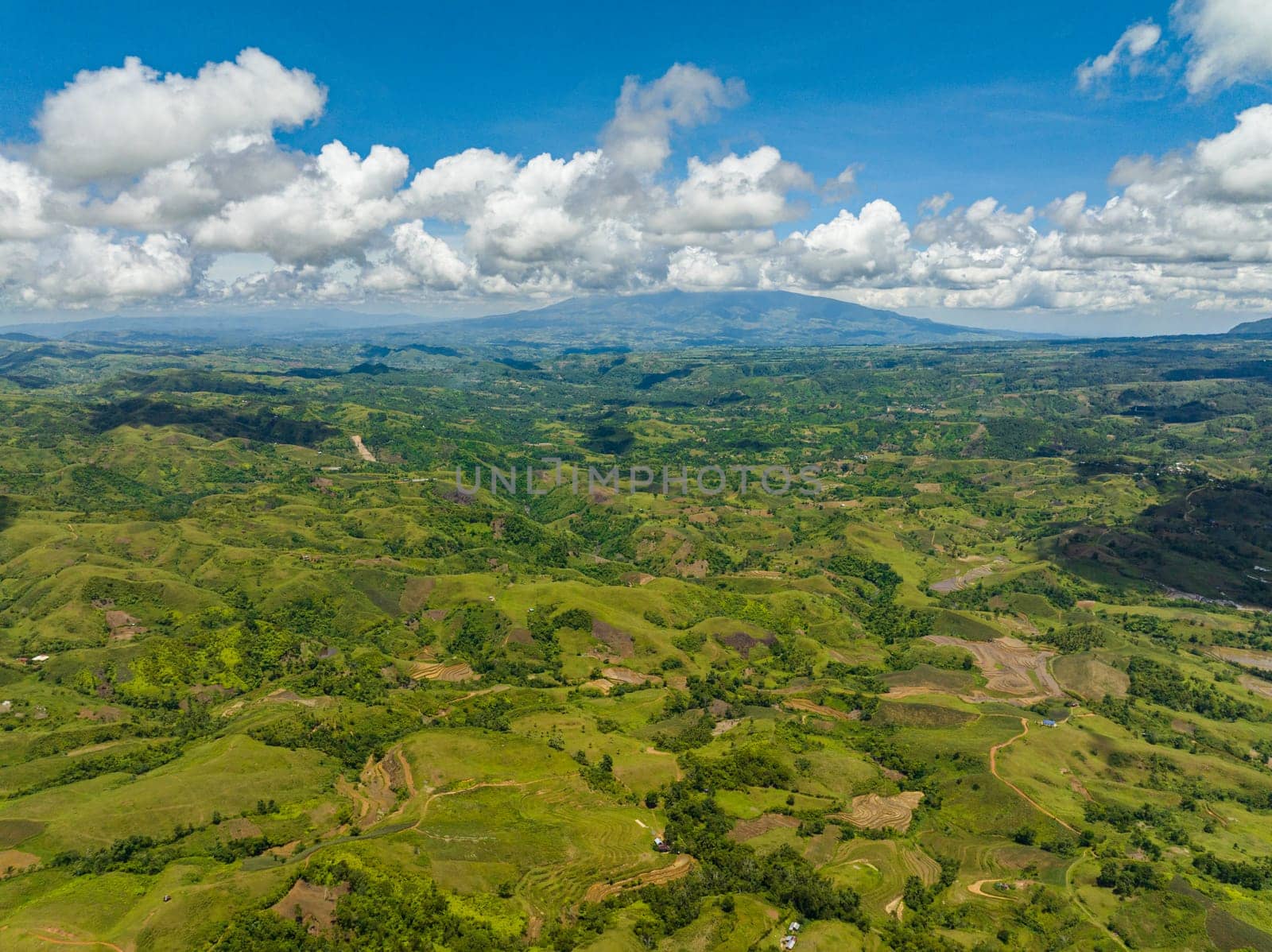 Farmland on a background of blue sky and clouds in a mountainous area. Negros, Philippines