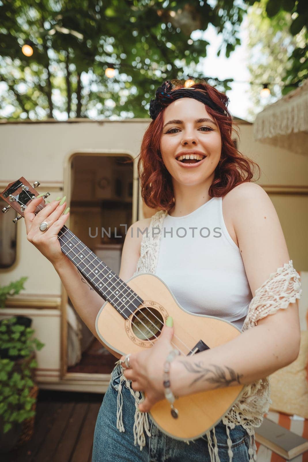 Happy hippie girl are having a good time with playing on guitar in camper trailer. Holiday, vacation, trip concept.High quality photo