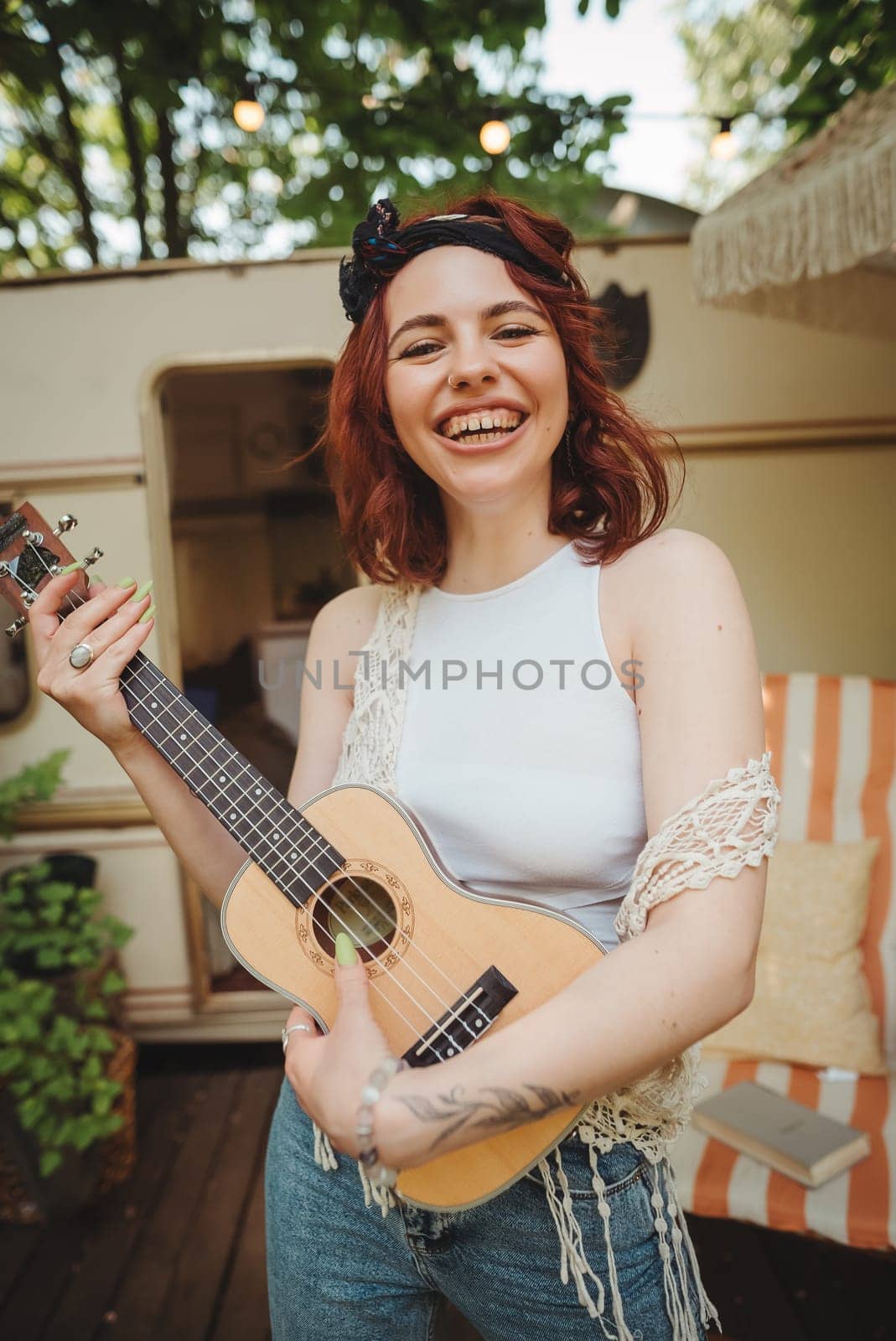 Happy hippie girl are having a good time with playing on guitar in camper trailer. Holiday, vacation, trip concept.High quality photo