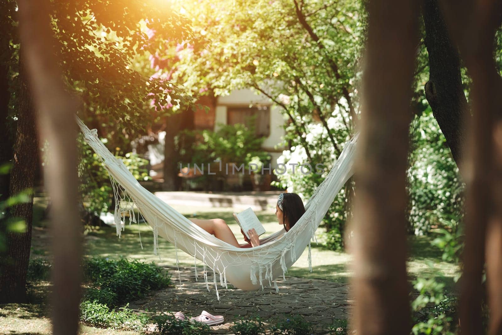 Happy hippie girl is reading a book in hammock having a good time with playing in camper trailer. Holiday, vacation, trip concept.High quality photo