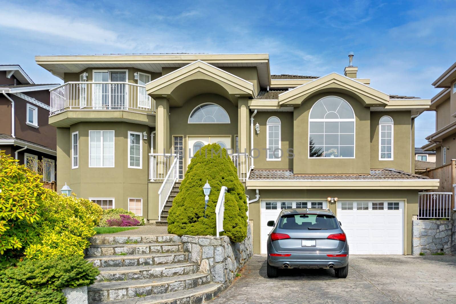 Luxury residential house with a car parked in front on cloudy day by Imagenet