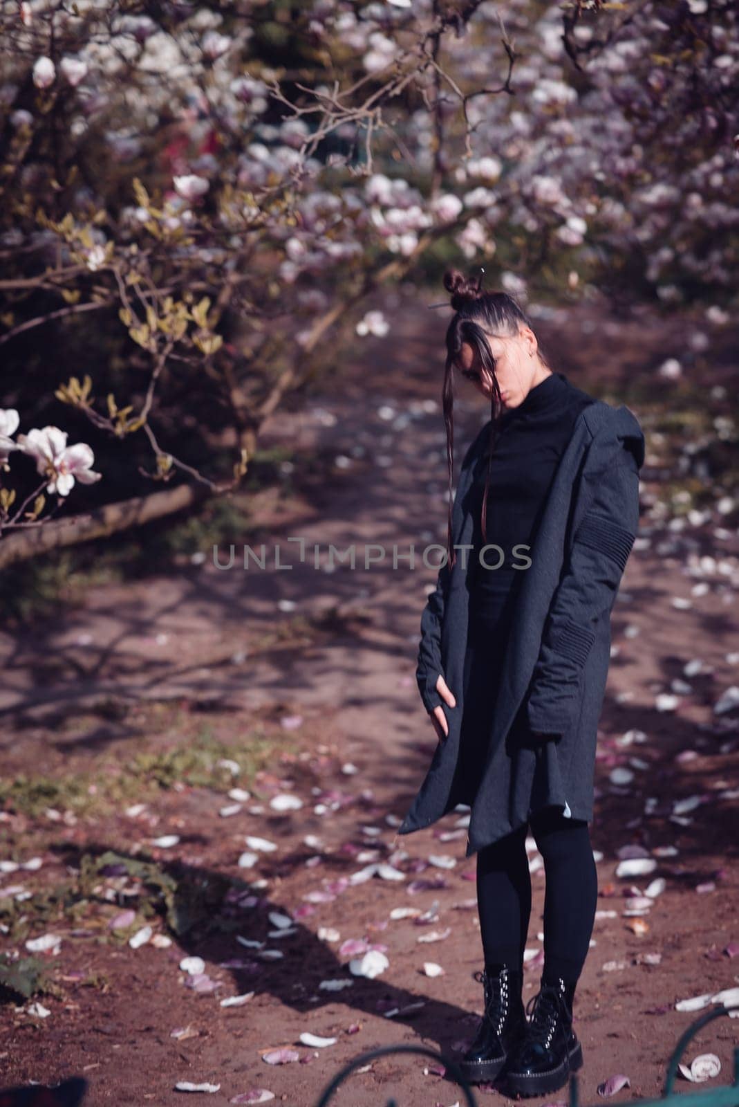 Beautiful dramatic young woman wearing black with cherry blossoms, sakura view. High quality photo