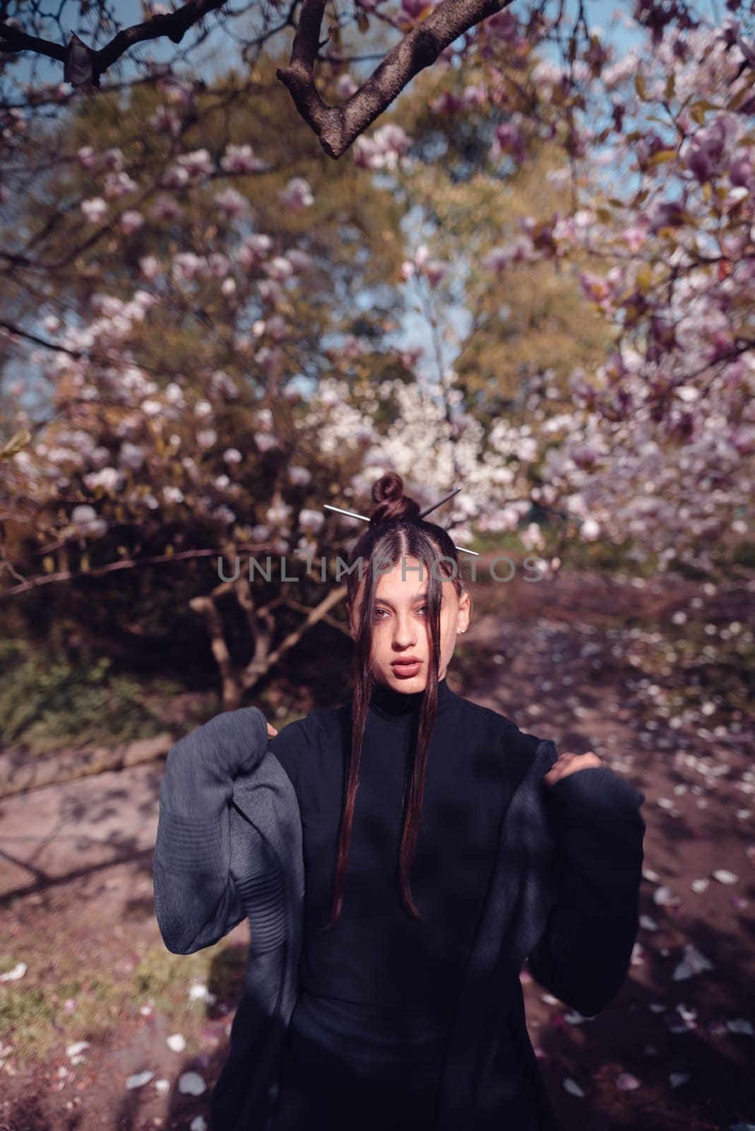 Beautiful dramatic young woman wearing kimono with cherry blossoms, sakura view. High quality photo
