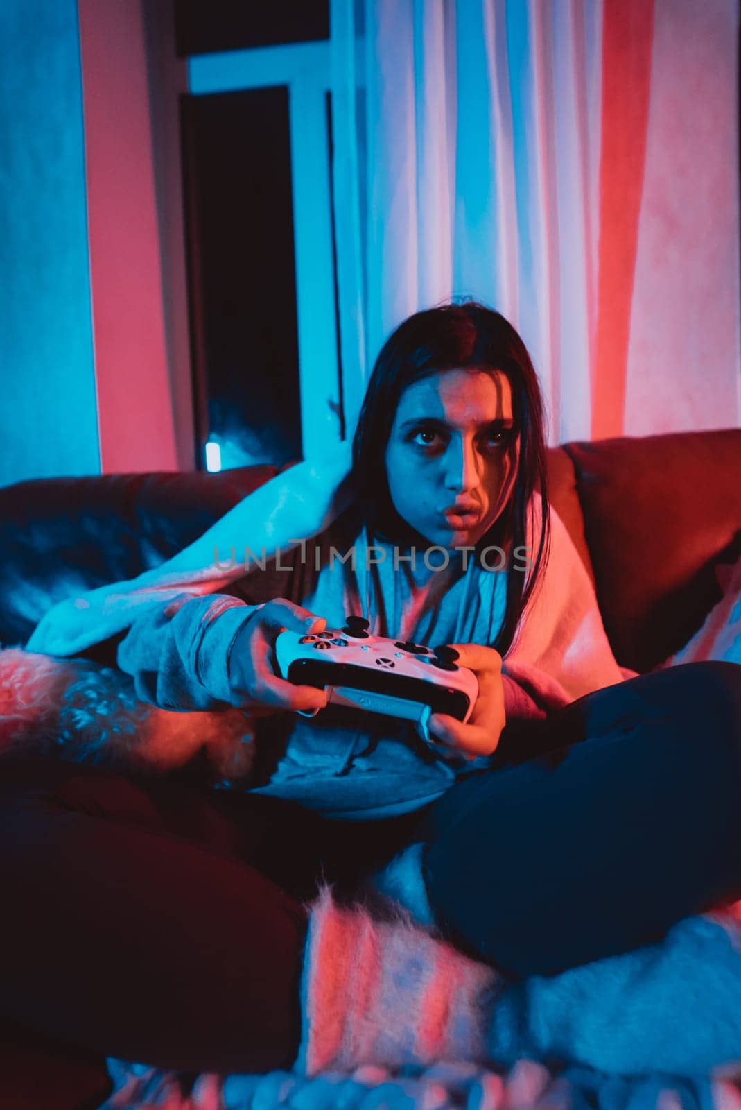 Close up portrait of A gamer or a streamer girl at home in a dark room with a game controller playing with her dog and sits in front of a monitor or TV. High quality photo