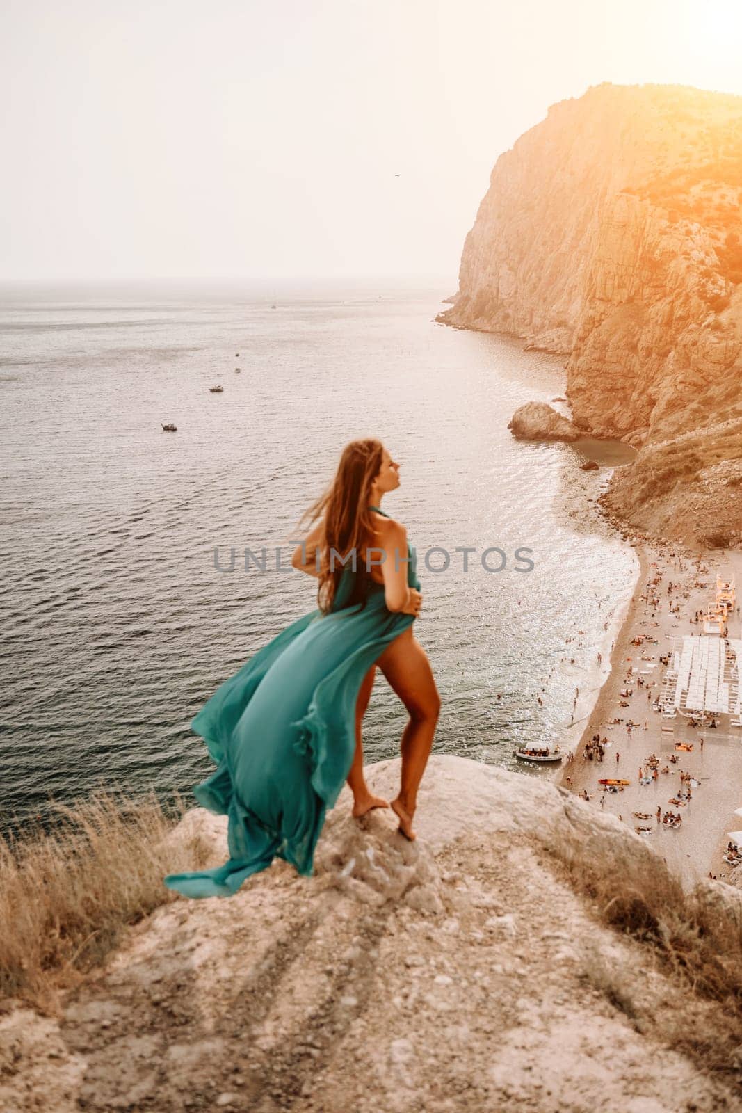 Woman sea trevel green dress. Side view a happy woman with long hair in a long mint dress posing on a beach with calm sea bokeh lights on sunny day. Girl on the nature on blue sky background