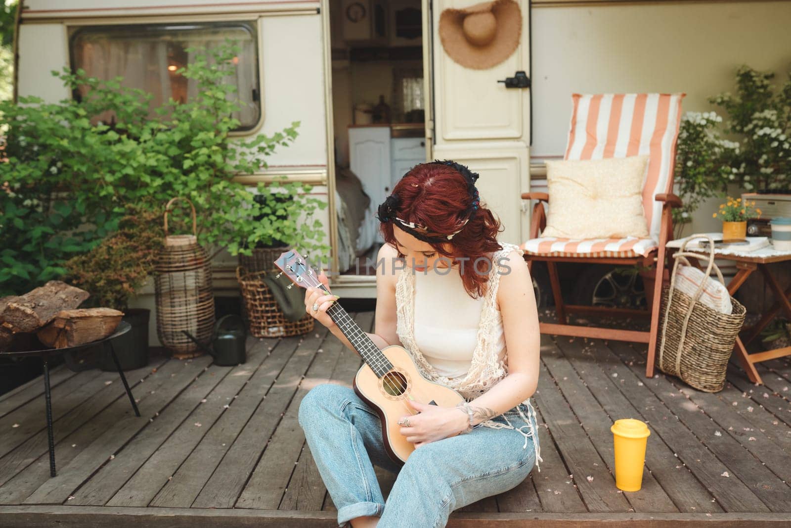 Happy hippie girl are having a good time with playing on guitar in camper trailer. Holiday, vacation, trip concept.High quality photo