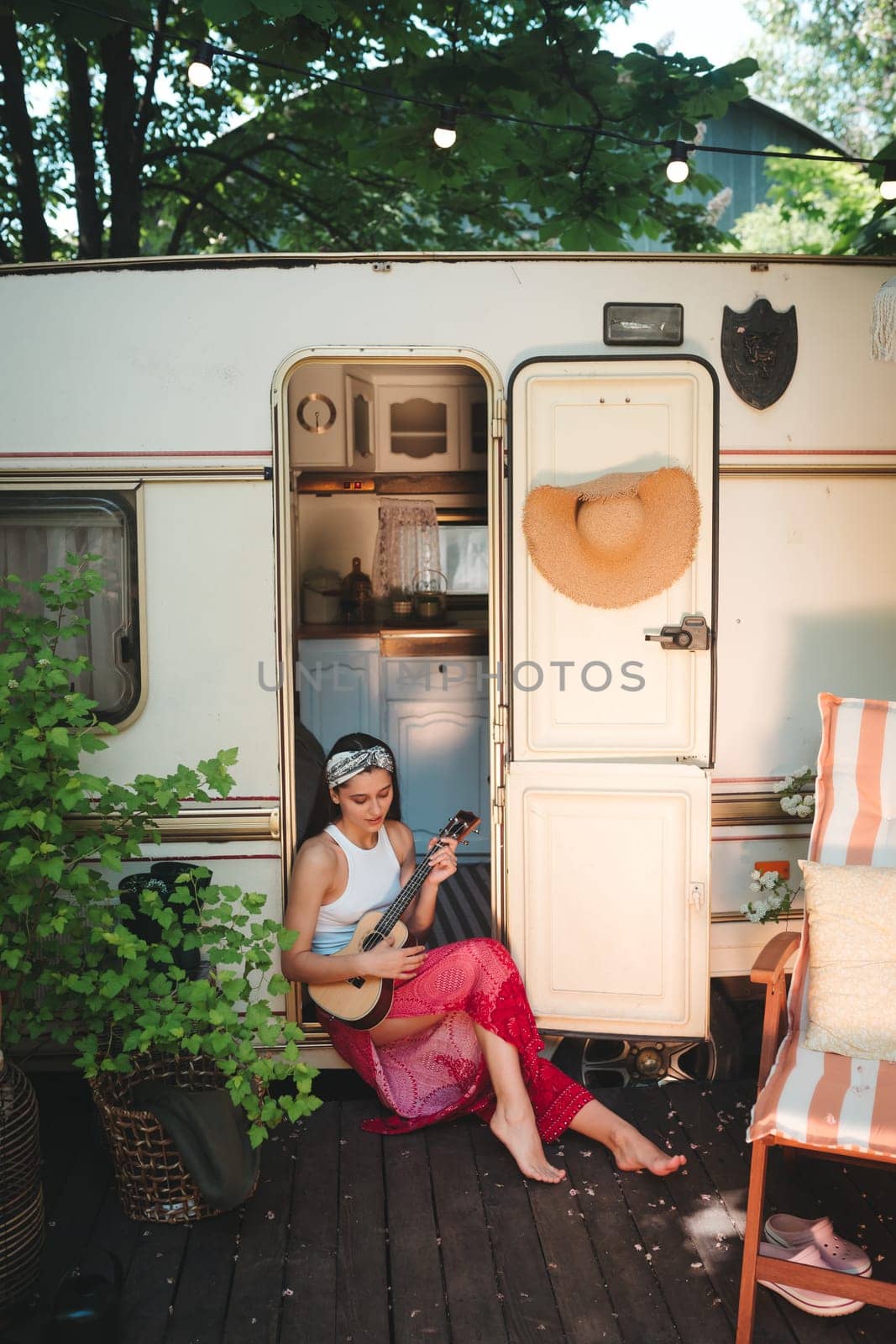 Happy hippie girl are having a good time with playing on guitar in camper trailer. Holiday, vacation, trip concept.High quality photo