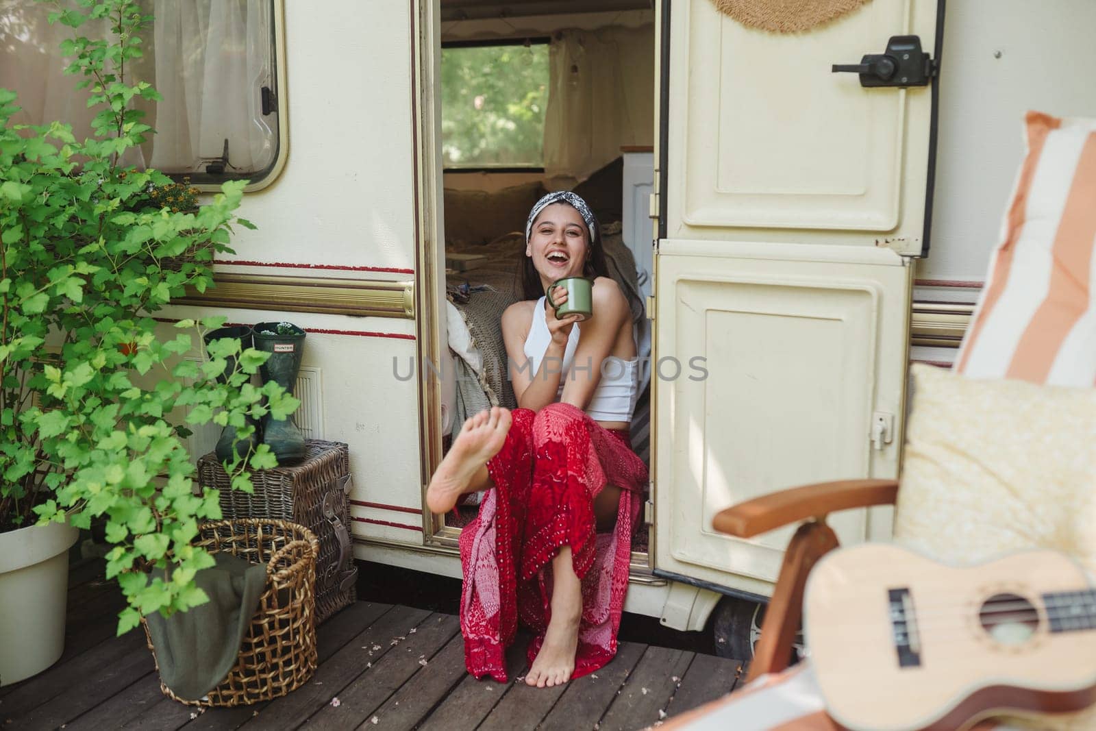 Happy hippie girl are having a good time with cup of tea in camper trailer. Holiday, vacation, trip concept.High quality photo
